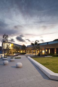 an outdoor courtyard with large white balls on the ground and grass in front of it