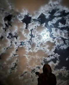 a person standing under a cloudy sky holding a camera