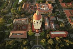 an aerial view of a large building with a clock on it's tower and surrounding trees