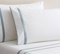 two white pillows with blue trim on top of a bed