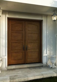 a large wooden door sitting on the side of a white building next to a lamp post