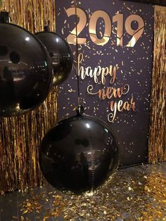 balloons and streamers in front of a new year's eve backdrop with gold confetti