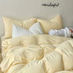 an unmade bed with yellow sheets and pillows