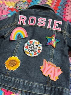 the back of a jean jacket with patches on it that say girls are magic and sunflowers