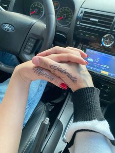 two people holding hands in front of a car with the word love on their fingers