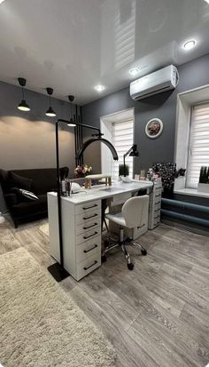 a white desk sitting on top of a hard wood floor next to a black couch