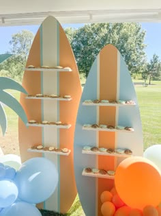 two surfboards and balloons are on display in front of an open field with trees