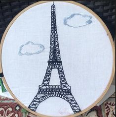 an embroidered picture of the eiffel tower with clouds in the sky behind it