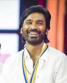 a man with a medal around his neck smiles at the camera while wearing a white shirt