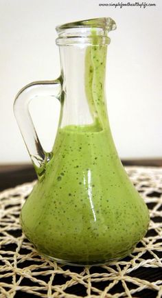 a pitcher filled with green liquid sitting on top of a table