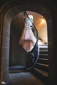 a wedding dress hanging on a spiral staircase