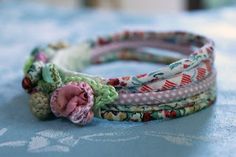 three bracelets with flowers on them sitting on a blue tablecloth covered table cloth