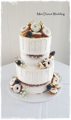 a three tiered white wedding cake with flowers on the top and sides, sitting on a table