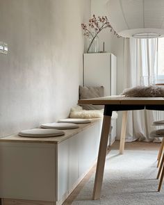 a dining room table with four plates on it and a bench in front of the window