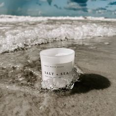 a candle sitting in the sand at the beach