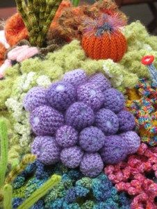 there are many crocheted balls and plants on the table top, all in different colors