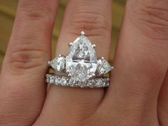 a woman's engagement ring with three pear shaped diamonds on the band and side stones