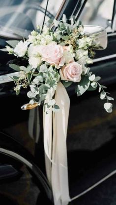 a bouquet of flowers is tied to the side of a black car with its door open