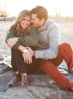 an image of a couple sitting together on the ground with their arms around each other