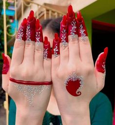 two hands with red and white manicures holding their fingers up to the camera