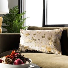 a bowl of fruit sitting on top of a table next to a couch with pillows