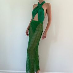 a woman standing in front of a white wall wearing a green dress with an open back