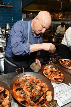 a man standing in front of two pans filled with food on top of a table