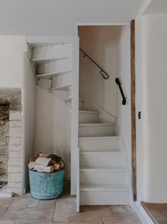 there is a basket on the floor in front of a stair case and fire place