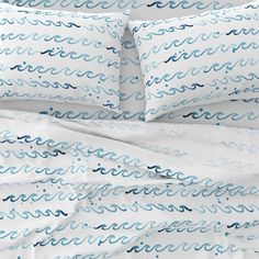 a bed with white sheets and blue waves on it