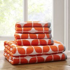 four orange and white towels stacked on top of each other in front of a window