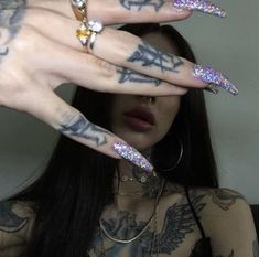 a woman with tattoos holding her hands up to the camera while wearing rings and piercings