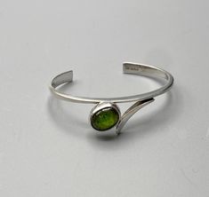 Forged Sterling Bracelet features a large, deep green Tourmaline cabochon.  Simple, elegant, this bracelet looks wonderful with long or short sleeves, suited for casual or formal wear. Green Cabochon Bracelets For Formal Occasions, Silver Bracelet With Cabochon, Green Cabochon Bracelet For Formal Occasions, Elegant Sterling Silver Cabochon Bracelet, Unique Silver Cuff Bracelet With Cabochon, Formal Green Cabochon Bracelets, Formal Green Cabochon Bracelet, Green Metal Cabochon Jewelry, Sterling Bracelets