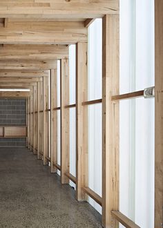 an empty room with wooden walls and flooring in the center is lined with windows