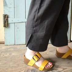 a person wearing yellow sandals standing in front of a door