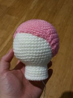 a crocheted pink and white object in the palm of a person's hand