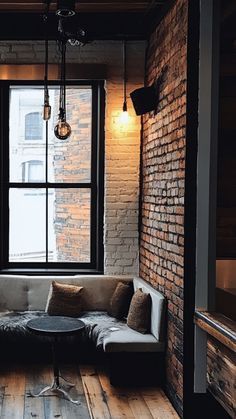 a living room filled with furniture next to a window and wooden floored walls in front of a brick wall