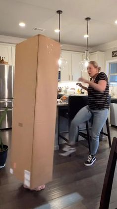 a woman standing next to a cardboard box in a kitchen