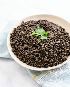 a white bowl filled with black lentils on top of a blue napkin