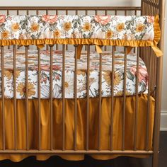 a baby crib with yellow ruffles and floral bedding