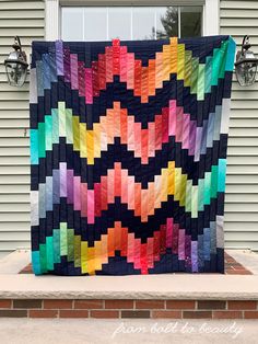 a colorful quilt hanging from the side of a house