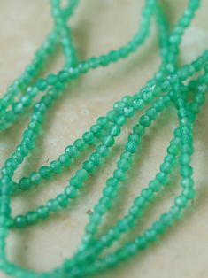 several green beads are laying on a table together, with one beaded in to the middle