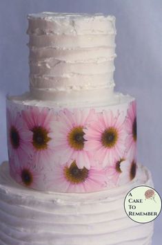 a white cake with pink and yellow flowers on it's tiered icing