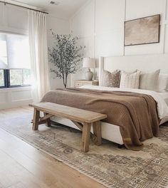 a bedroom with a large bed, wooden bench and window sill in the corner