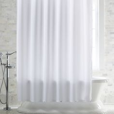 a white shower curtain in a bathroom next to a bathtub and sink with a faucet