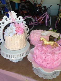 two cakes decorated with pink and white frosting, one has a gold horse on top