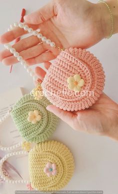 two crocheted coin purses are being held by a woman's hand