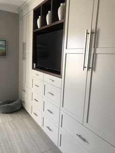 a large entertainment center with white cabinets and gray carpeted flooring, along with a dog bed