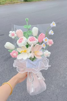 a person is holding a bouquet of flowers in their hand on the side of the road