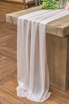 a wooden bench with a white table cloth draped over it and flowers on the back