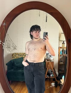 a shirtless man taking a selfie in front of a mirror with his cell phone